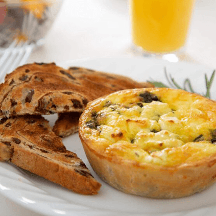A plate of a baked frittata alongside slices of toasted bread and a glass of orange juice.