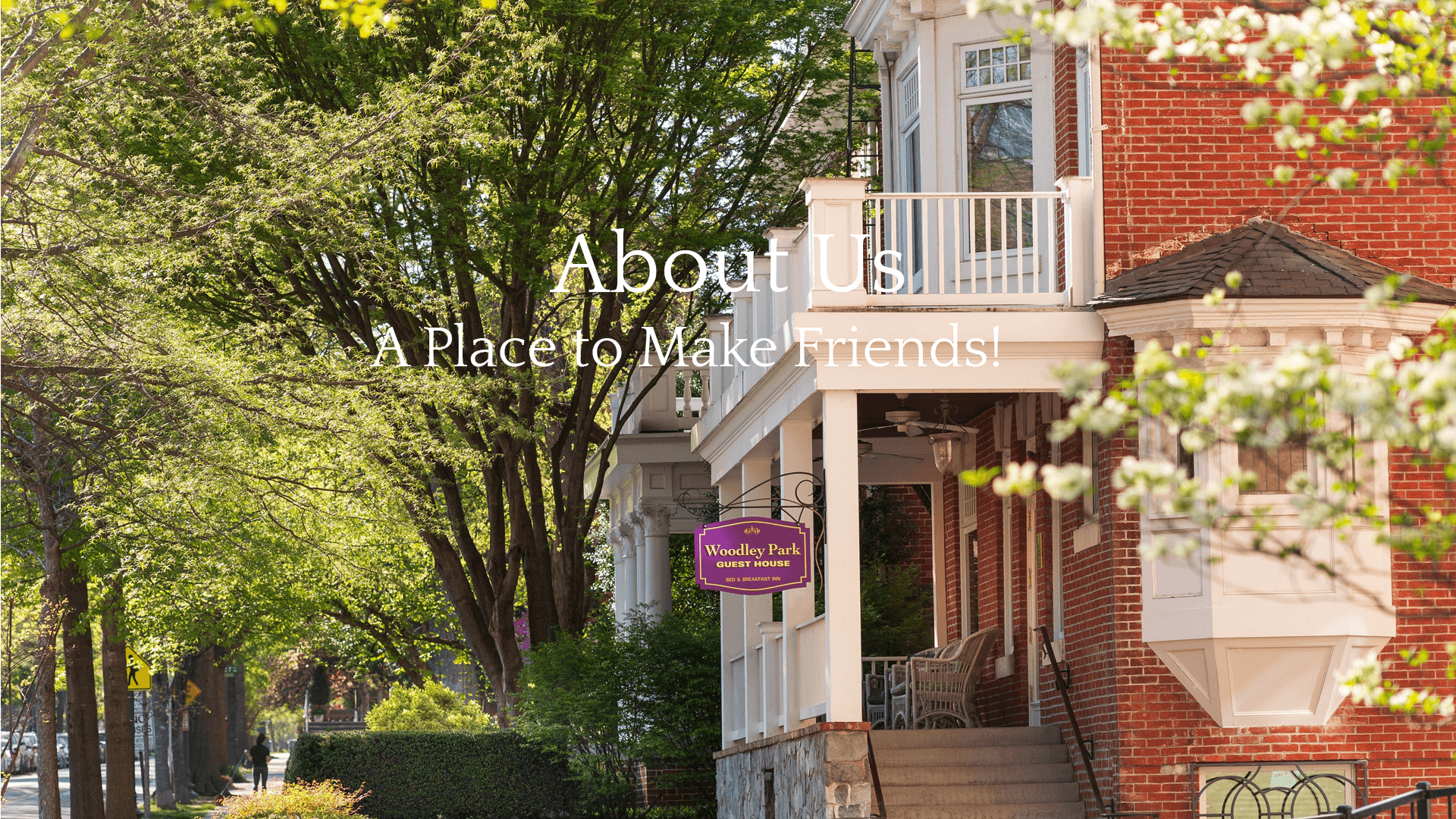 A charming red-brick guest house surrounded by lush greenery, featuring a welcoming sign.