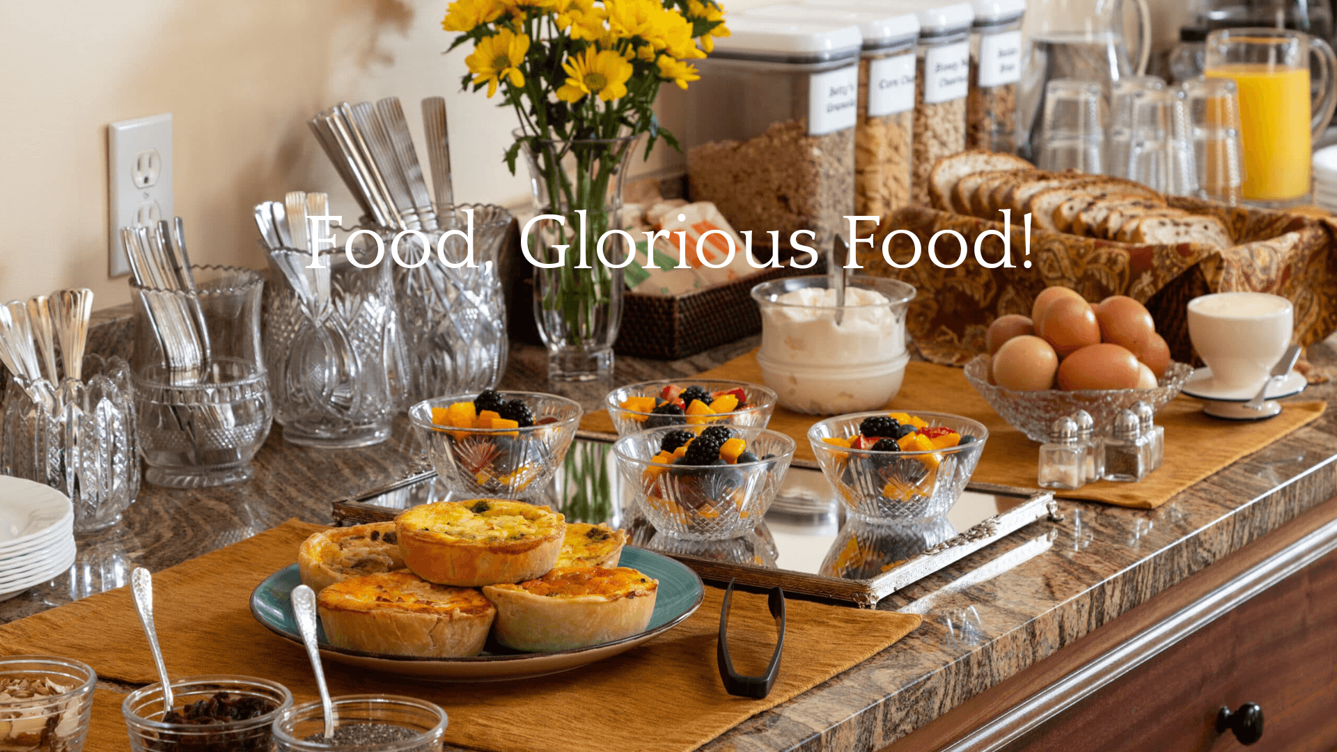 A beautifully arranged breakfast spread featuring pastries, fresh fruits, eggs, and yogurt.