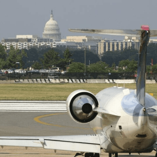 A plane sits on a runway with the U.S. Capitol building visible in the background.