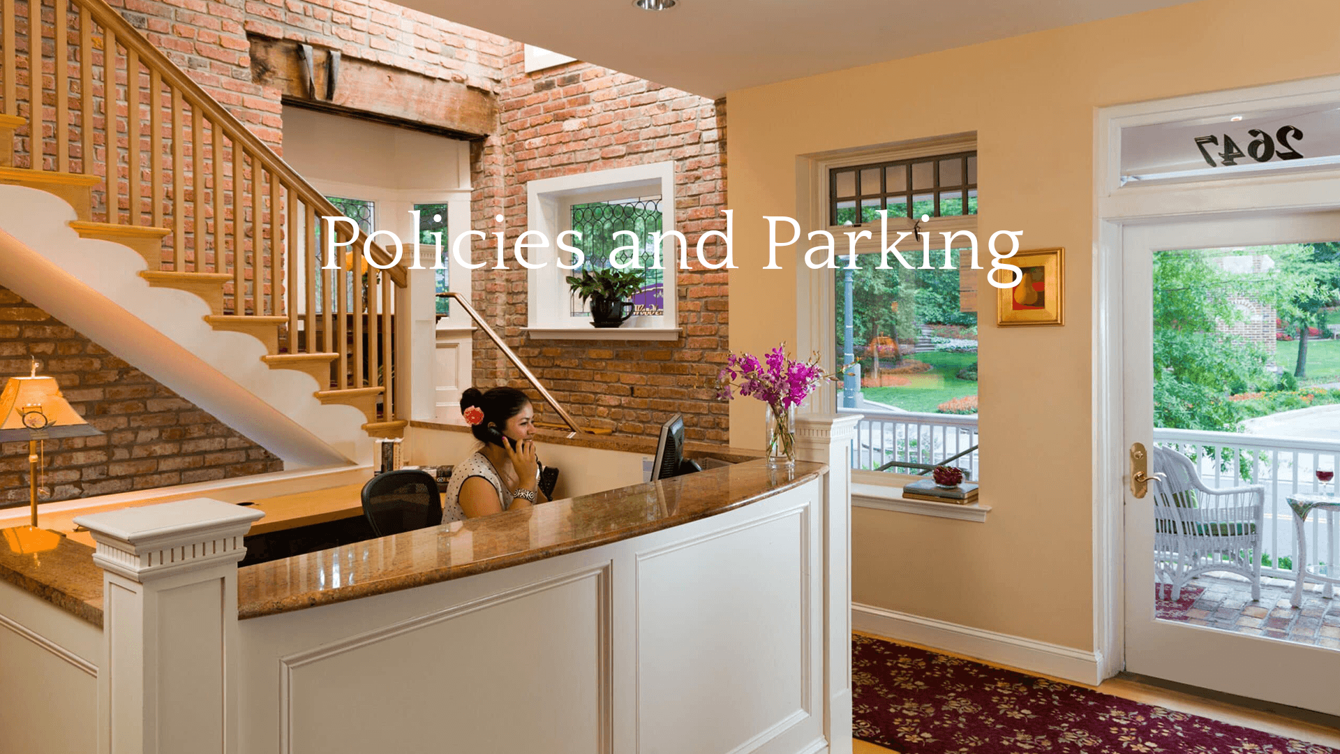 A receptionist on the phone at a welcoming front desk with brick walls and decorative flowers.