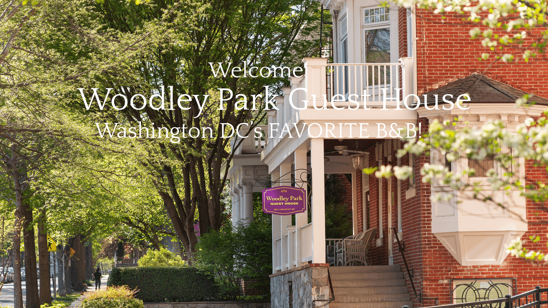 Exterior view of the Woodley Park Guest House with a welcoming sign in a lush green setting.